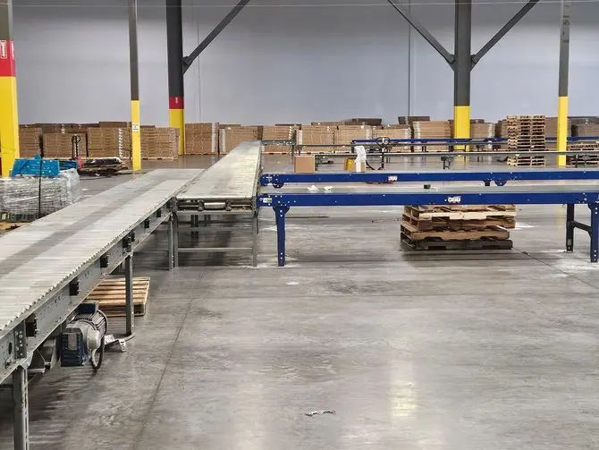 Roller and belt conveyor lines installed across an empty warehouse floor